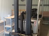 a forklift in a storage room with a table and chairs