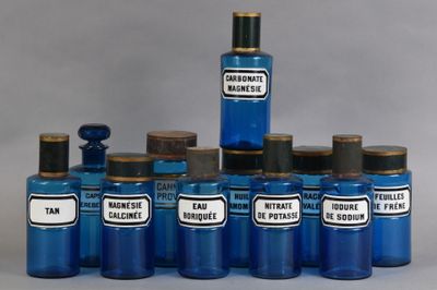plusieurs bouteilles en verre bleu, munies d'étiquettes, posées sur une table