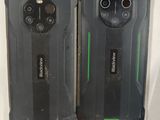 two black and green cell phones sitting next to each other on a white surface
