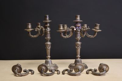 trois chandeliers en argent posés sur une table devant un fond noir