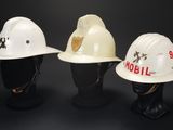 three white hard hats are lined up on a mannequin head