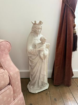 une statue représentant une femme tenant un enfant dans ses bras, à côté d'une chaise