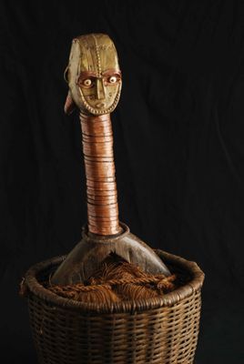 une photo représentant une sculpture en bois représentant une tête d'homme dans un panier en osier