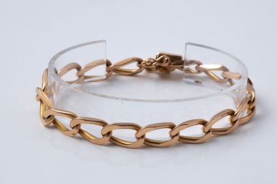 gros plan d'un bracelet en or sur une surface blanche