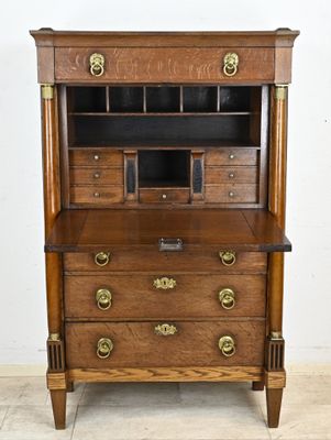 une vieille commode en bois avec des tiroirs et des poignées en laiton dans une pièce