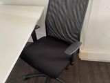 a black office chair sitting in front of a white desk