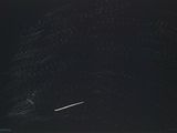 an image of a jet flying through the night sky over a field