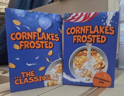 two boxes of cornflakes frosted cereal sitting on a table