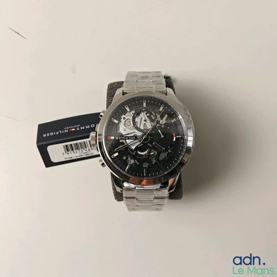 La montre a un cadran noir et un bracelet argenté.