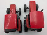 two red toy tractors sitting on a white surface