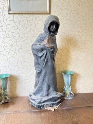une statue représentant une femme debout sur une table, avec deux vases