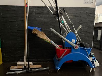 plusieurs balais et porte-balais dans une pièce aux murs en briques