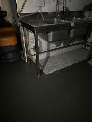 a sink in the corner of a room with a metal counter