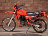 a red dirt bike parked in front of a brick wall