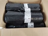 quatre rouleaux de sacs poubelle noirs dans une boîte en carton
