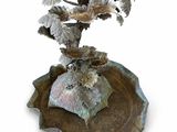 a metal vase with a plant in it on a plate