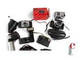 many different types of cameras and accessories laid out on a white surface