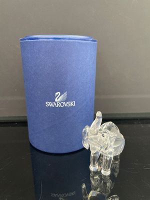 un petit éléphant en cristal posé à côté d'une tasse bleue