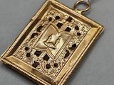 a close up of a gold pendant with a cross on it