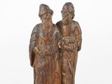 une vieille figurine en bois représentant deux hommes debout l'un à côté de l'autre