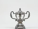 an antique silver plated trophy on a stand on a white background