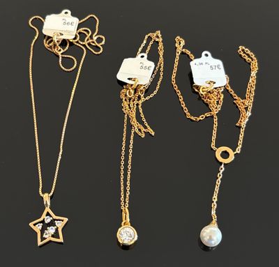 trois colliers en or avec des breloques et une étoile sur une chaîne