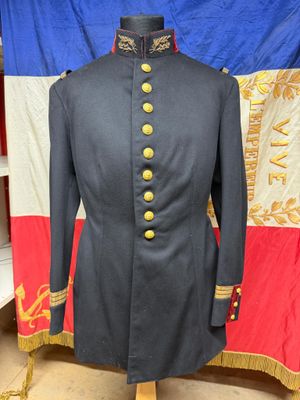 un manteau militaire noir à boutons dorés, posé sur un présentoir pour mannequin