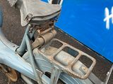 a blue scooter that is parked in front of a wall with graffiti on it