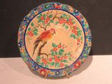 a colorful plate with a bird on it sitting on a table