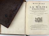un vieux livre ouvert posé sur une table, à côté d'un autre livre