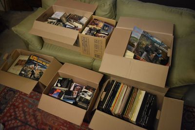 de nombreux cartons remplis de livres posés sur un canapé dans un salon