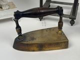 a small antique iron with a wooden handle on a table