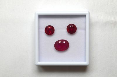 une boîte blanche contenant trois pierres précieuses rouges