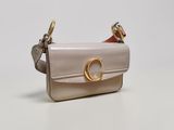 un petit sac à main beige muni d'un anneau doré sur la poignée
