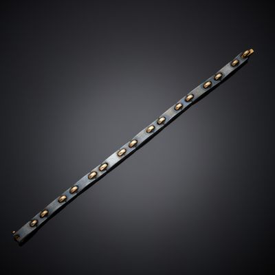 a close up of a metal bracelet with rivets on a black background