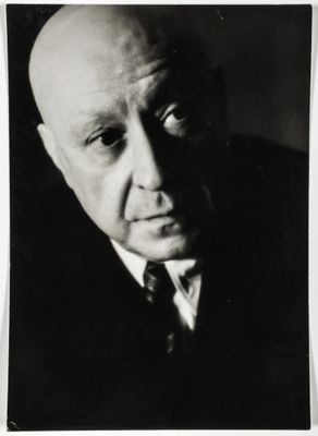 black and white photograph of a bald man in a suit and tie