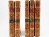 three old books sitting on top of each other on a white surface