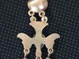a close up of a silver pendant with bells on a black background