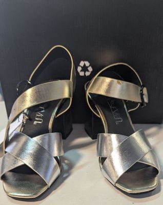 une paire de sandales argentées pour femme, présentées dans une boîte