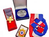 trois médailles et une médaille dans une boîte posée sur une surface blanche