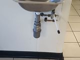 un lavabo dans un coin de la salle de bains, avec un robinet fixé au mur