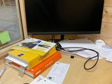 un bureau sur lequel se trouvent un écran, des livres et d'autres objets