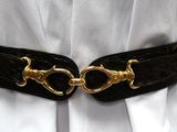 a woman wearing a black belt with gold buckles on it