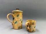 Deux objets en poterie sont posés sur une table : l'un est jaune et l'autre est vert.