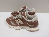 brown and white new balance shoes on a white surface
