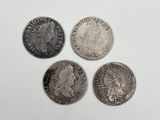 quatre types différents de pièces d'argent posées sur une surface blanche