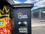 une boîte à pizza ornée d'une couronne, à côté d'une poubelle