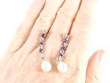 an image of a woman ' s hand holding a pair of purple and white pearls