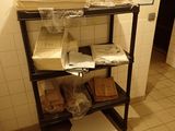 une étagère noire sur laquelle sont posées des boîtes et des sacs, dans une salle de bains