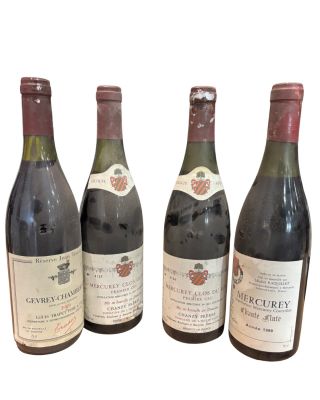 quatre bouteilles de vin sont alignées sur une surface blanche